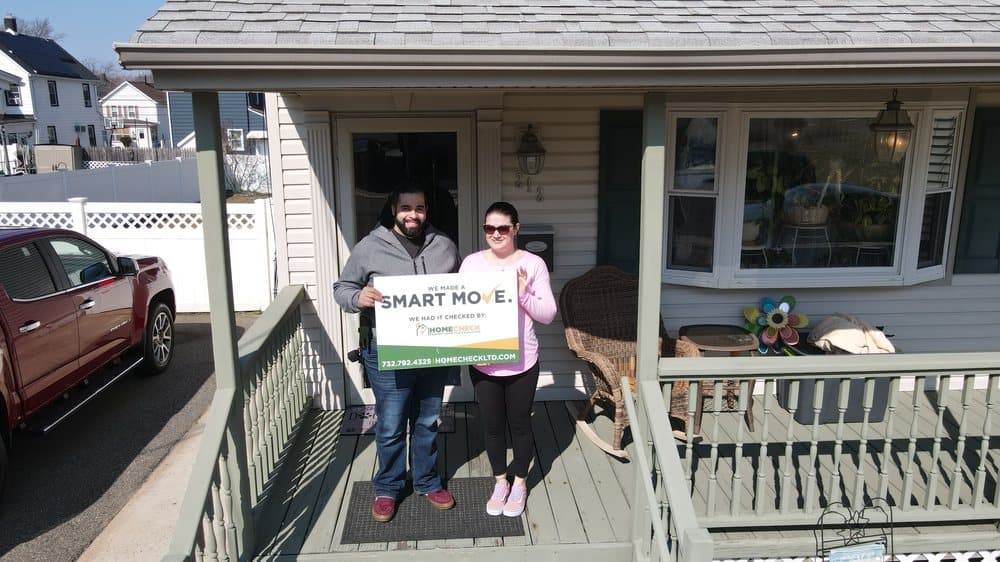 HomeCheck clients on the front porch of their newly inspected New Jersey home, holding a Smart Move sign