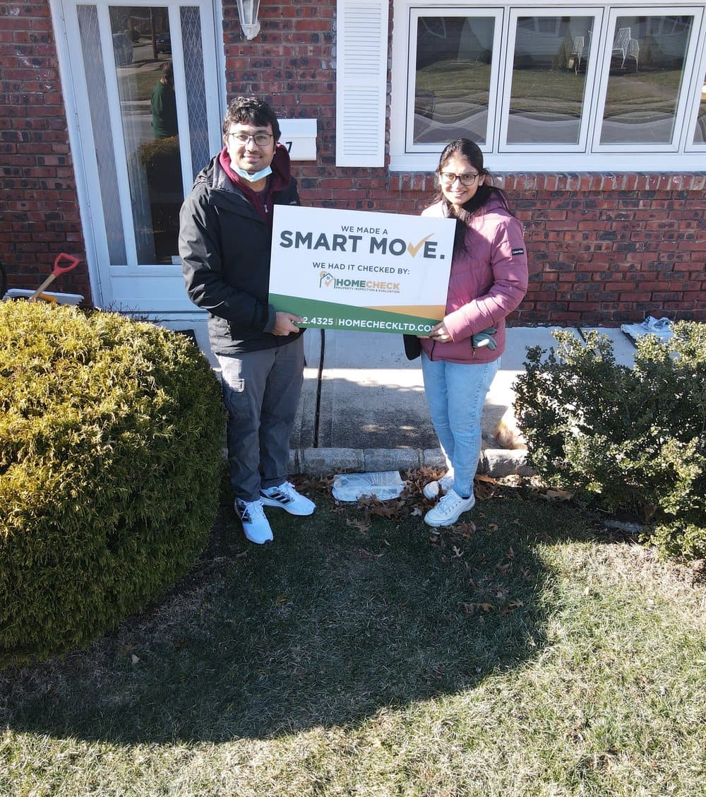 HomeCheck clients in the front yard of their newly inspected New Jersey home, holding a Smart Move sign