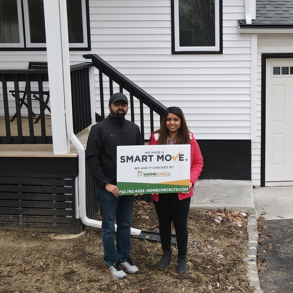 HomeCheck clients outside their newly inspected New Jersey home, holding a Smart Move sign