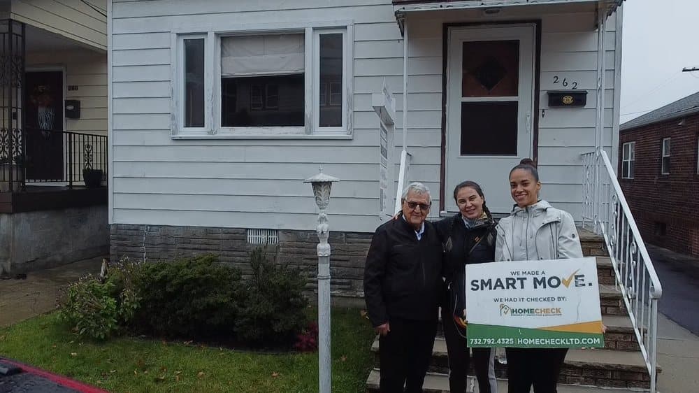 HomeCheck clients outside their newly inspected New Jersey home, holding a Smart Move sign